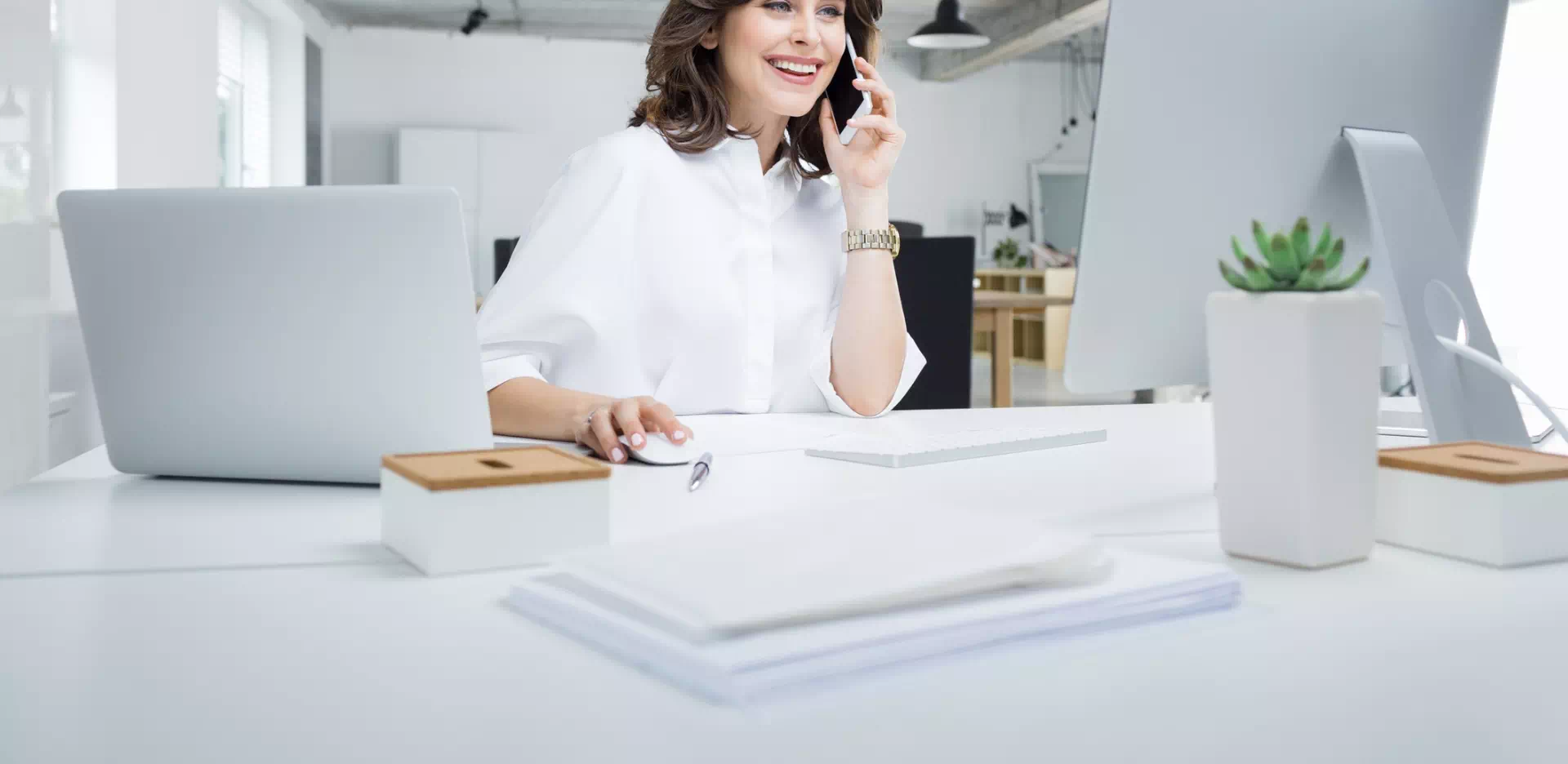 Kobieta ubrana w białą koszulę pracująca w biurze