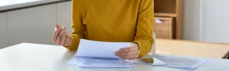 Osoba z żółtej bluzce przeglądająca dokumenty